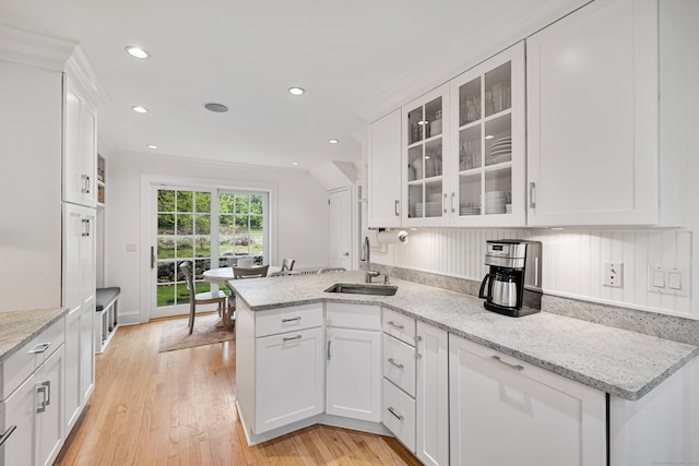 kitchen featuring a sink, white cabinetry, glass insert cabinets, a peninsula, and recessed lighting