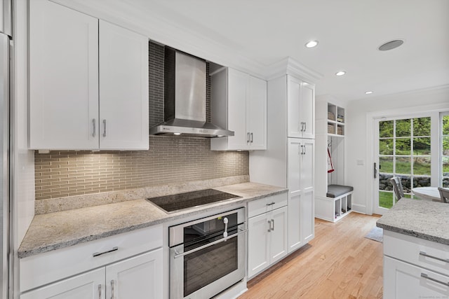 kitchen with wall chimney exhaust hood, stainless steel oven, black electric stovetop, white cabinets, and recessed lighting