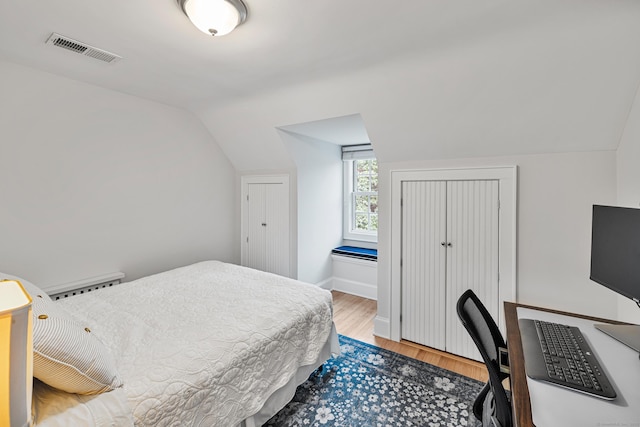 bedroom featuring baseboard heating, wood finished floors, vaulted ceiling, and a desk
