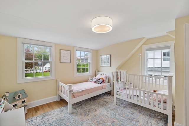 bedroom featuring wood finished floors, vaulted ceiling, and baseboards