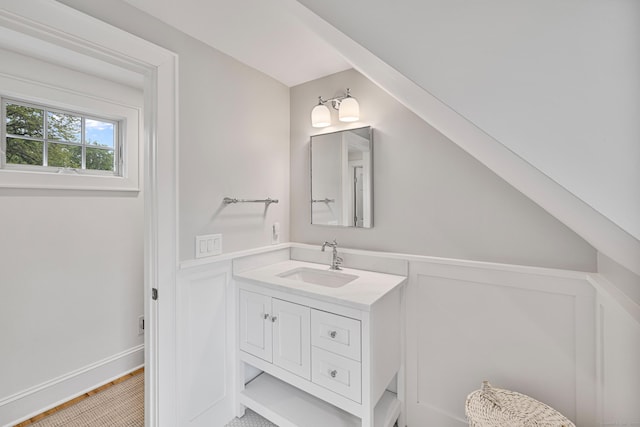 bathroom featuring vanity, wainscoting, and a decorative wall
