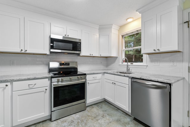 63 Summit St Apt 16, Manchester, CT 06040 - kitchen featuring appliances with stainless steel finishes, a sink, decorative backsplash, white cabinetry, and a textured ceiling