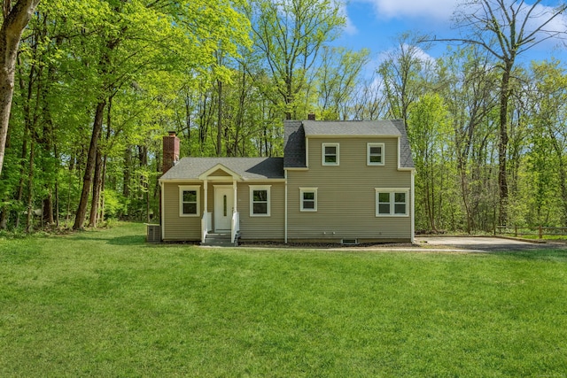 view of front of house featuring a shingled roof, a chimney, a front lawn, and cooling unit