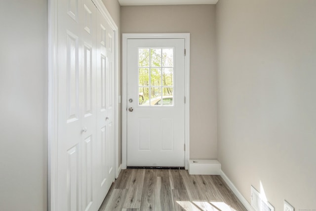 doorway with light wood-style flooring and baseboards