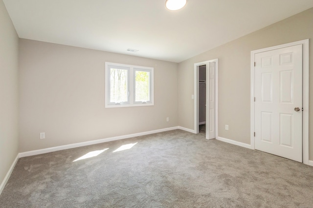 unfurnished bedroom featuring carpet, baseboards, and a spacious closet