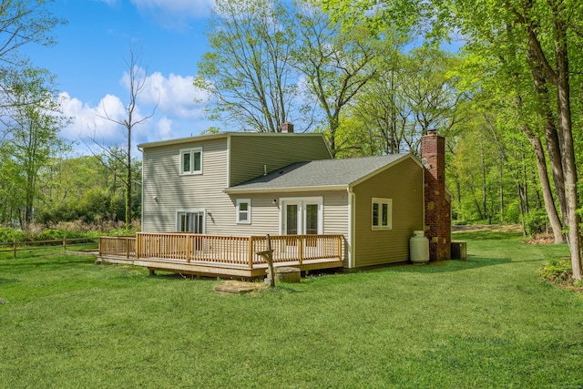 rear view of property featuring a chimney, a deck, and a lawn