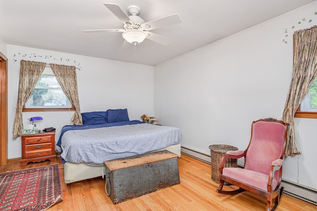 bedroom with a baseboard radiator, multiple windows, and light wood finished floors