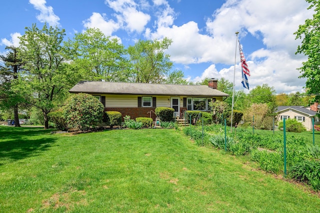 ranch-style house with brick siding, a front yard, and a chimney