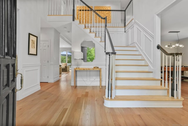 681 Old Stamford Rd, New Canaan, CT 06840 - entrance foyer featuring light wood-type flooring, stairway, a decorative wall, wainscoting, and a towering ceiling