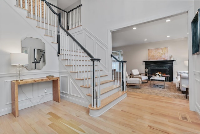 681 Old Stamford Rd, New Canaan, CT 06840 - stairs with a decorative wall, wood finished floors, a lit fireplace, and recessed lighting
