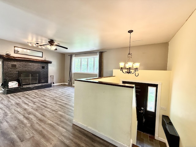 foyer with a fireplace, baseboards, wood finished floors, a ceiling fan, and a chandelier