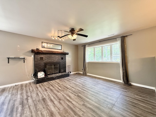 unfurnished living room featuring a ceiling fan, a fireplace, wood finished floors, and baseboards