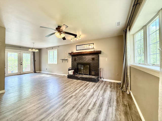 unfurnished living room with baseboards, wood finished floors, a brick fireplace, and ceiling fan