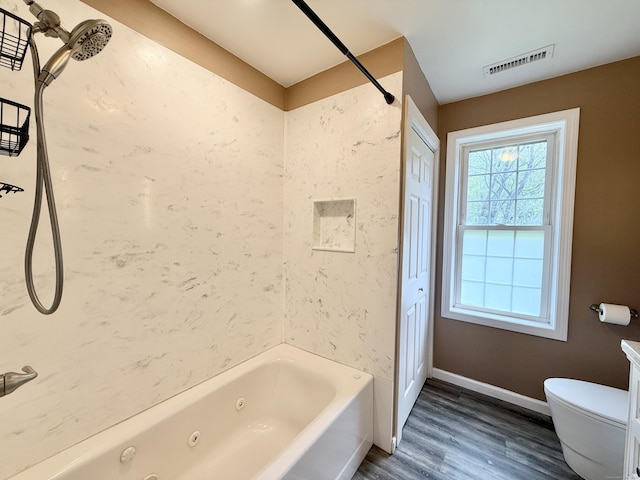 bathroom featuring wood finished floors, toilet, a combined bath / shower with jetted tub, and baseboards
