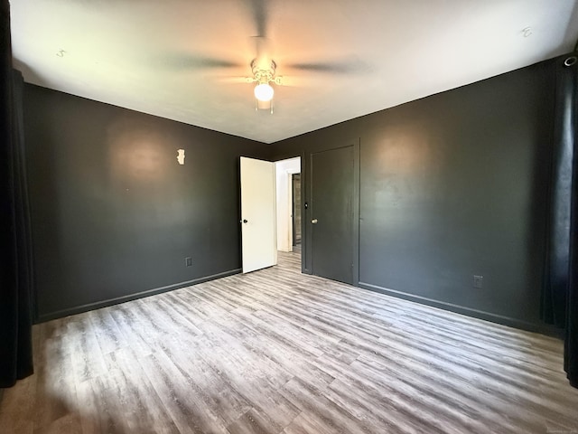 unfurnished room with wood finished floors, ceiling fan, and baseboards