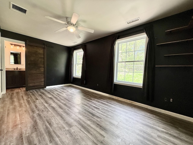 spare room featuring plenty of natural light, wood finished floors, ceiling fan, and baseboards