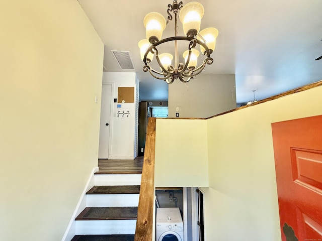 stairs featuring a chandelier and washer / dryer