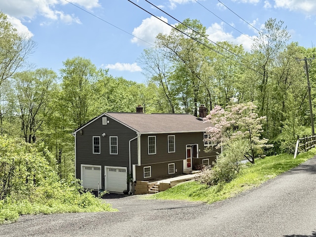 split foyer home with a chimney, driveway, and a garage
