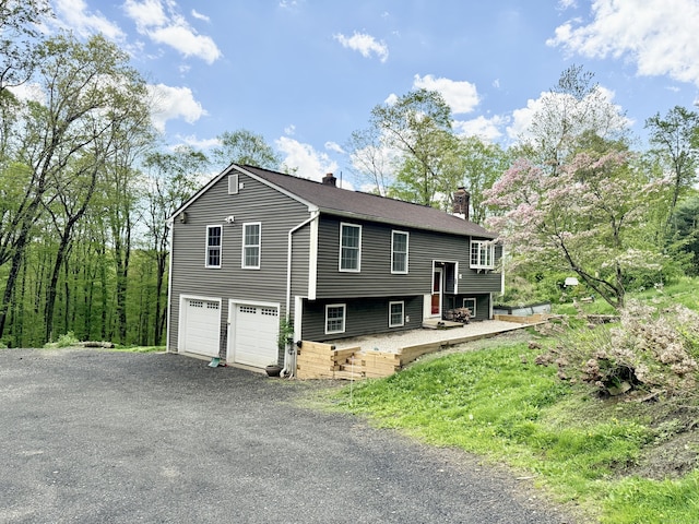 raised ranch with a chimney, a garage, and driveway