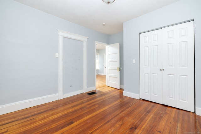 unfurnished bedroom featuring hardwood / wood-style flooring, a closet, and baseboards