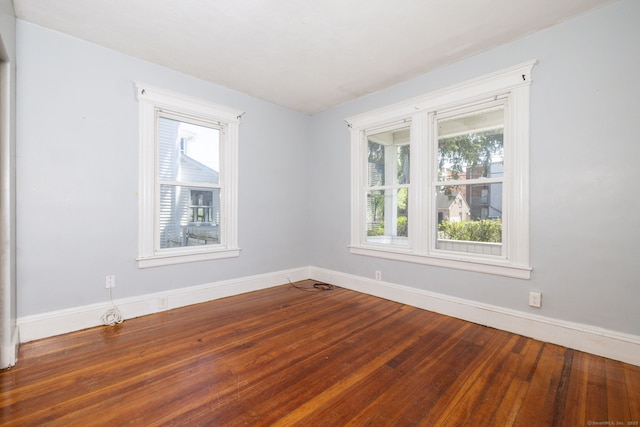unfurnished room with healthy amount of natural light, baseboards, and wood finished floors
