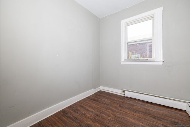empty room with wood finished floors, baseboard heating, and baseboards