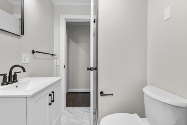 half bathroom with toilet, vanity, ornamental molding, and marble finish floors