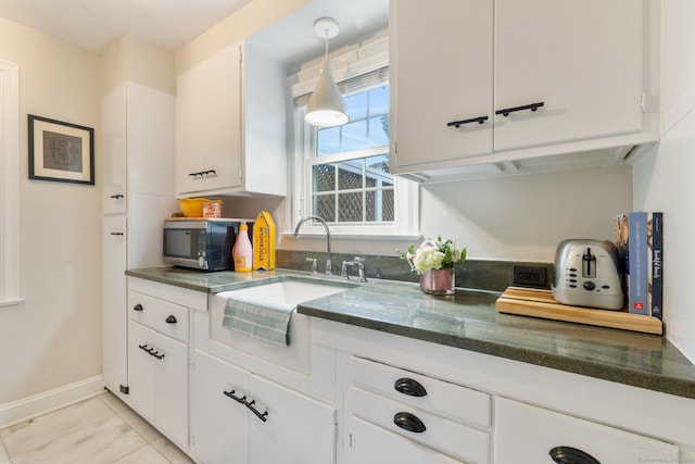 85 5th St, Stamford, CT 06905 - kitchen with stainless steel microwave, a sink, white cabinetry, and dark stone countertops