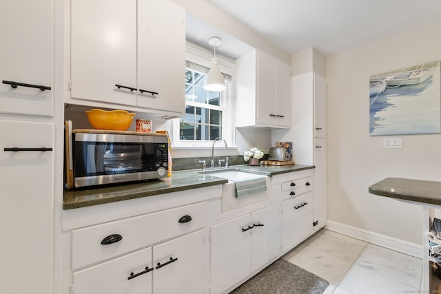 85 5th St, Stamford, CT 06905 - kitchen featuring a sink, stainless steel microwave, white cabinetry, dark countertops, and baseboards