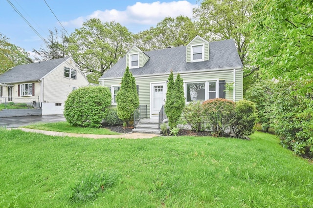 new england style home featuring a front lawn and roof with shingles
