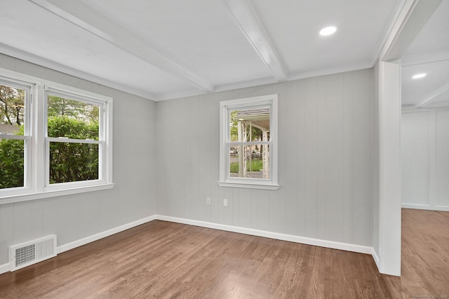 unfurnished room featuring healthy amount of natural light, wood finished floors, beam ceiling, and baseboards