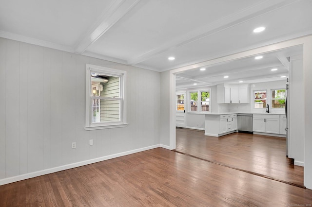 unfurnished living room with wood finished floors, beamed ceiling, baseboards, a sink, and recessed lighting