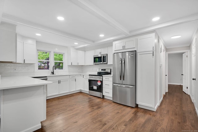 kitchen featuring appliances with stainless steel finishes, a sink, dark wood finished floors, white cabinets, and light countertops