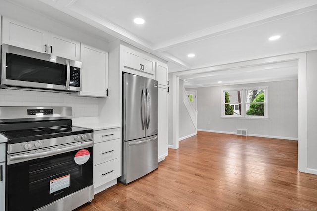 kitchen with stainless steel appliances, light countertops, light wood-type flooring, white cabinets, and recessed lighting