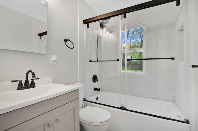 bathroom featuring toilet, vanity, and combined bath / shower with glass door
