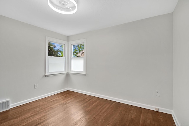 unfurnished room featuring baseboards and dark wood-style flooring