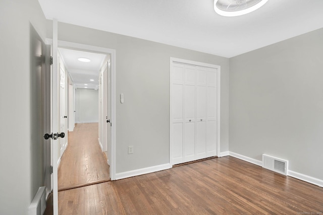 unfurnished bedroom with wood finished floors, baseboards, and a closet