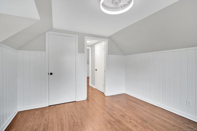 additional living space with wood finished floors, lofted ceiling, and a wainscoted wall