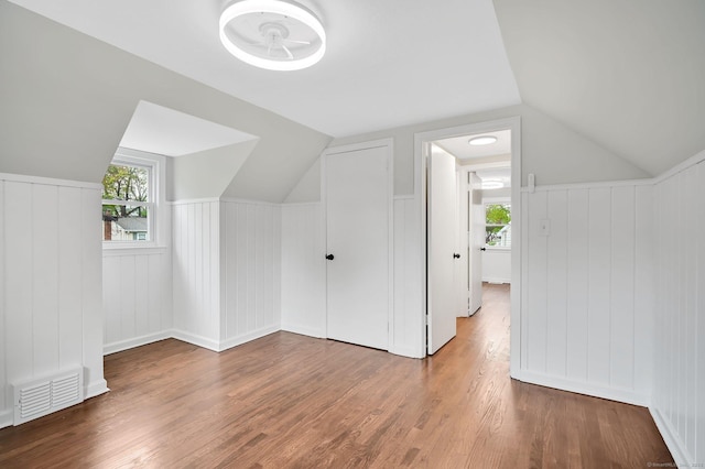 bonus room with plenty of natural light, wood finished floors, lofted ceiling, and a decorative wall