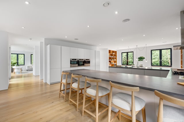 kitchen featuring dark countertops, modern cabinets, recessed lighting, light wood-style flooring, and white cabinetry
