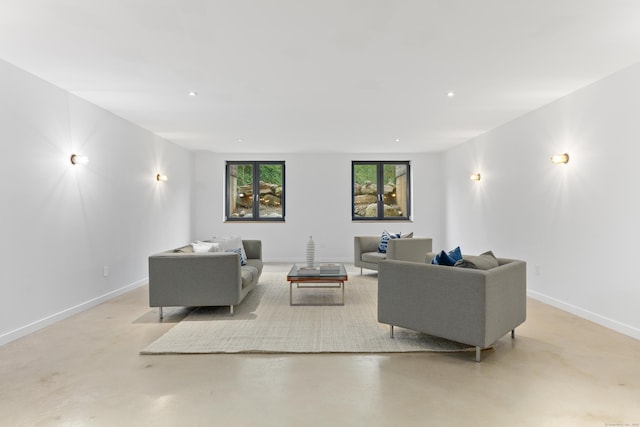 living area featuring finished concrete floors, baseboards, and recessed lighting