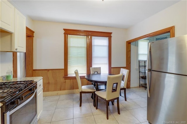 19 5th St, Ansonia, CT 06401 - dining room featuring a wainscoted wall, wood walls, light tile patterned flooring, and baseboards