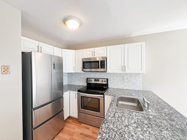 279 New Haven Ave Apt H, Milford, CT 06460 - kitchen with stainless steel appliances, a sink, light wood finished floors, decorative backsplash, and white cabinetry