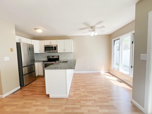 279 New Haven Ave Apt H, Milford, CT 06460 - kitchen featuring stainless steel appliances, a peninsula, light wood-type flooring, and decorative backsplash