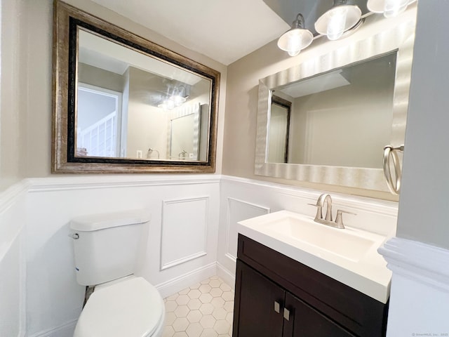 279 New Haven Ave Apt H, Milford, CT 06460 - bathroom with a decorative wall, a wainscoted wall, tile patterned floors, toilet, and vanity