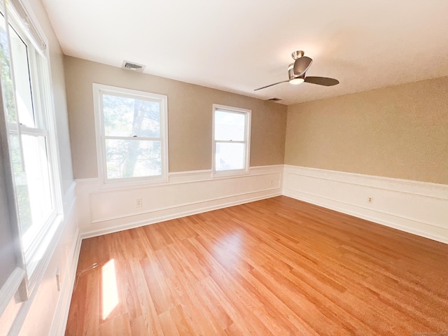 279 New Haven Ave Apt H, Milford, CT 06460 - empty room featuring light wood-style floors, wainscoting, healthy amount of natural light, and ceiling fan