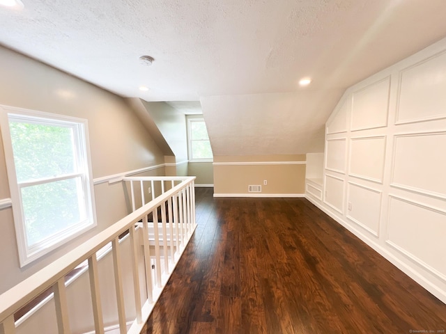 279 New Haven Ave Apt H, Milford, CT 06460 - bonus room featuring dark wood-style flooring, vaulted ceiling, healthy amount of natural light, a textured ceiling, and baseboards