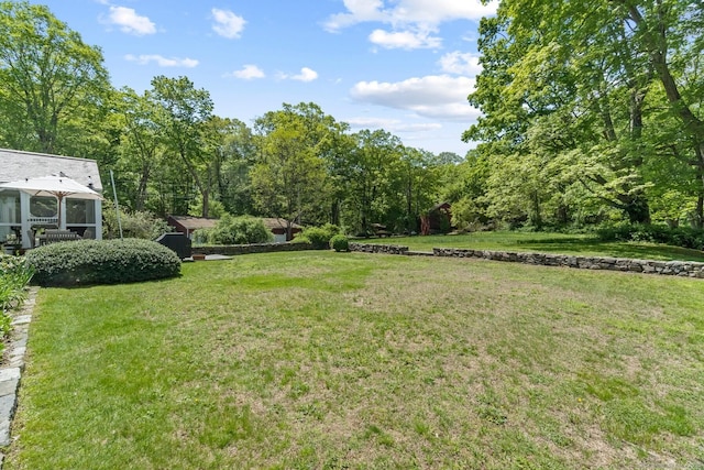 view of green lawn featuring a sunroom