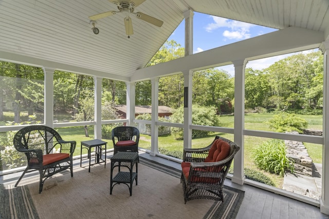 sunroom / solarium with ceiling fan, lofted ceiling, plenty of natural light, and view of scattered trees