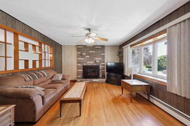 11 Jamestown Rd, Hamden, CT 06518 - living area featuring a baseboard heating unit, ceiling fan, wooden walls, light wood-style flooring, and a brick fireplace
